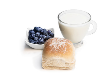 Freshly baked wheat bun with blueberry and glass of milk isolated on white