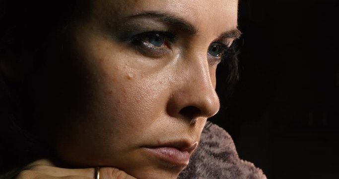 Close-up Dolly Shot Dramatic Young Female Face. Serious Calm Emotion Housewife thinking while sitting in dark room