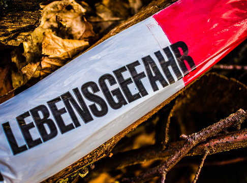 Absperrschild mit Aufschrift in deutsch Lebensgefahr in englisch Risk of death