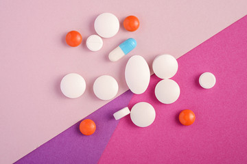 Pills and tablets on bright pink, violet and purple background, healthcare medical concept, antibiotics and cure, top view