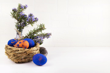 A nest with colored easter eggs on white copyspace background