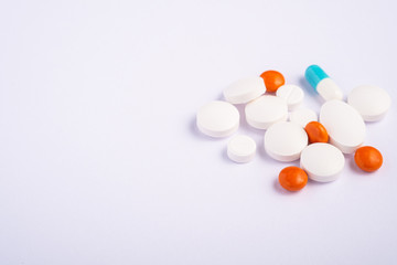 Pills and tablets on bright white background, healthcare medical concept, antibiotics and cure, angle view copy space