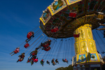 chairoplane, chain caroussel at traditional, historic fun fair in Bremen, Germany on a sunny day with blurred People and blue sky in the background