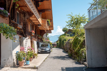 Obraz premium Cozy narrow street in Switzerland. Flowers in flower pots, greens