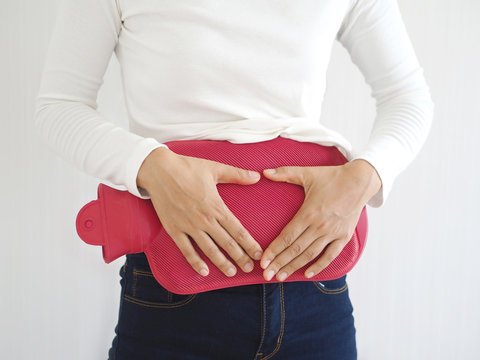 period pain and dysmenorrhea in asian woman , she use hand touching red hot water bag or bottle on white background use for health care concept.