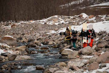 Group of people with snowboards hiking in mountains