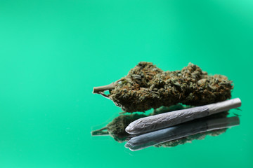 Cannabis branch and joint, red football styled grinder isolated on a green background
