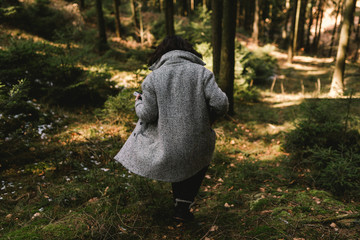 Frau mit grauen Wollmantel im Wald 
