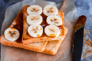 Two delicious toasts with salted caramel and bananas on the table.