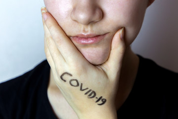 Girl touching face with hands with covid-19 written on it. Stop spreading virus. Don't touch face with dirty hands