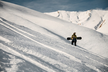 Male freerider with snowboard poses on mountain slope