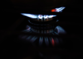 Blue and white flames of natural gas burning stove top closeup