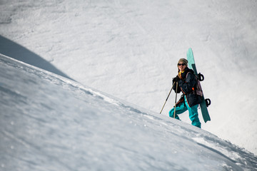 Fototapeta na wymiar Female hiker goes up the mountain with snowboard