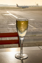 Glass of champagne on a table in an airport business lounge with an aircraft burred in the background