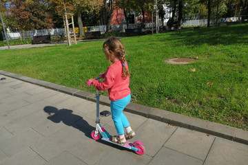 little girl, 4 and a half years old, plays with her scooter