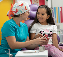 Smiling dentist observing girl in consultation