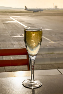 Glass Of Champagne On A Table In An Airport Business Lounge With An Aircraft Burred In The Background