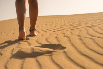 Close up view of beautiful women legs walking on the desert sand enjoying travel and outdoor leisure activity at the beach or dunes - concept of summer holiday vacation and nudist people