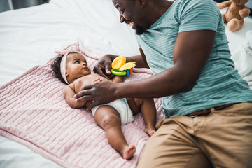 Happy Afro American father playing with newborn daughter