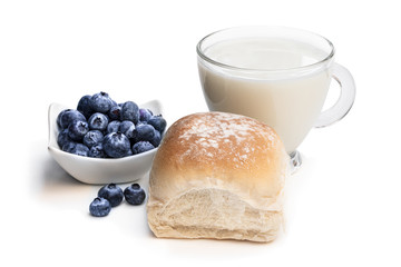 Freshly baked wheat bun with blueberry and glass of milk isolated on white