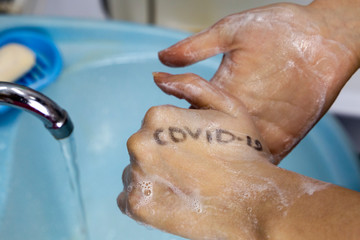 Fototapeta premium Hands with covid-19 written on them. Dangerous touch concept, prevent spread of virus, wash your hands with soap