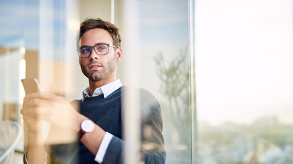 Young businessman using his cellphone in his office