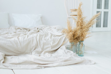 Light bedroom in Scandinavian style in beige and neutral colors. Pampas grass in glass vases.