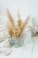 Pampas dry grass in blue vases in white bedroom