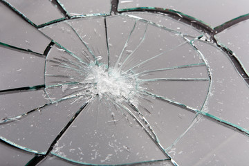 Broken glass with gray reflection and black cracks