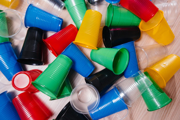 A large pile of multicolored plastic cups scattered on the floor. Pollution of the environment by...