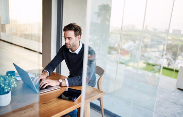 Young businessman working on his laptop at a dining table