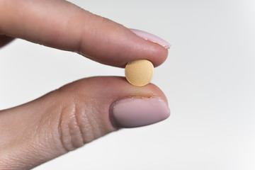 Woman holds small antiviral pill in hand. Drug researched in laboratory speeds up coronavirus recovery in early trials of COVID-19. Active against virus SARS-CoV-2 and ebola disease curation