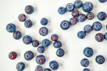 Blueberries scattered on a white wooden background. Top view