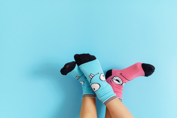 children's legs in funny socks raised up on a blue background, feet having fun, creative concept