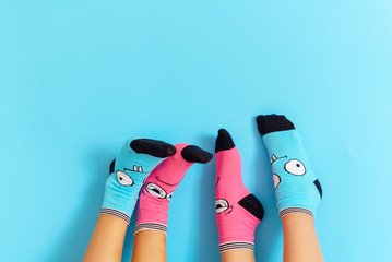 children's legs in funny socks raised up on a blue background, feet having fun, creative concept
