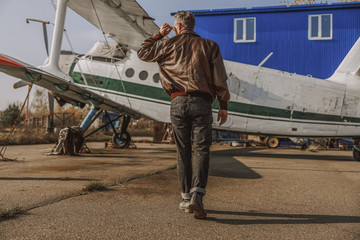 Stylish young man is walking to the plane