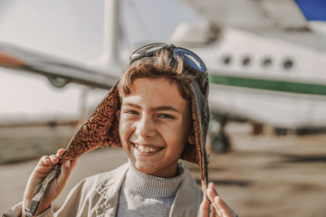 Happy little child is standing near airplane