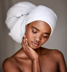 Woman with her hair wrapped in a towel touching her cheek