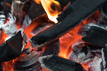 Charcoal burning with orange fire and white and gray ashes preparing for a barbecue in spring and summer