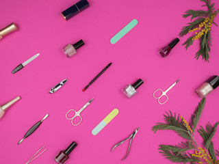 Obraz premium Beauty nail accessories and flowers of Mimosa on a pink background.