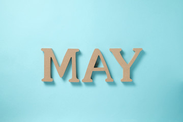 「MAY」の木でできたアルファベットのブロック 水色背景 俯瞰