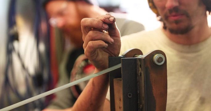 Bladesmith deburring a blade on belt grinder