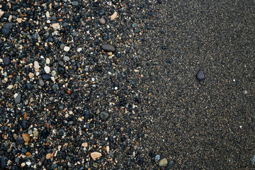 Texture of black sand and small stones on it. Blacksand paper abstract texture