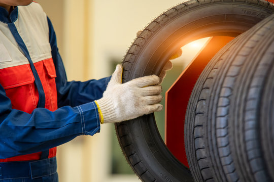 Mechanic in uniform is examining a tire while working in auto service,Mechanic with tires concept.