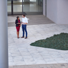 Two diverse young businesspeople talking outside of an office building