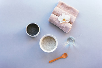 Black and green clay, spoon and towel on light gray table. Ingredients for natural skin care.