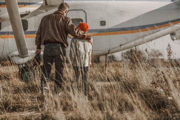 Young father hugging his son near big airplane