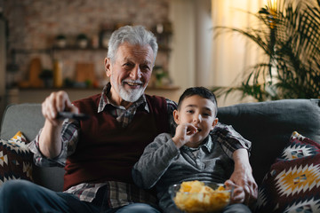 Grandfather and grandson watching television. Grandfather and grandson watching television at home.