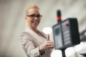 Businesswoman showing thumbs up. Young businesswoman in factory..