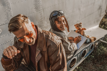 Happy cute kid holding book near his father